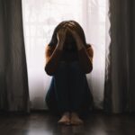 woman sitting on the floor holding her head struggling with different types of depression