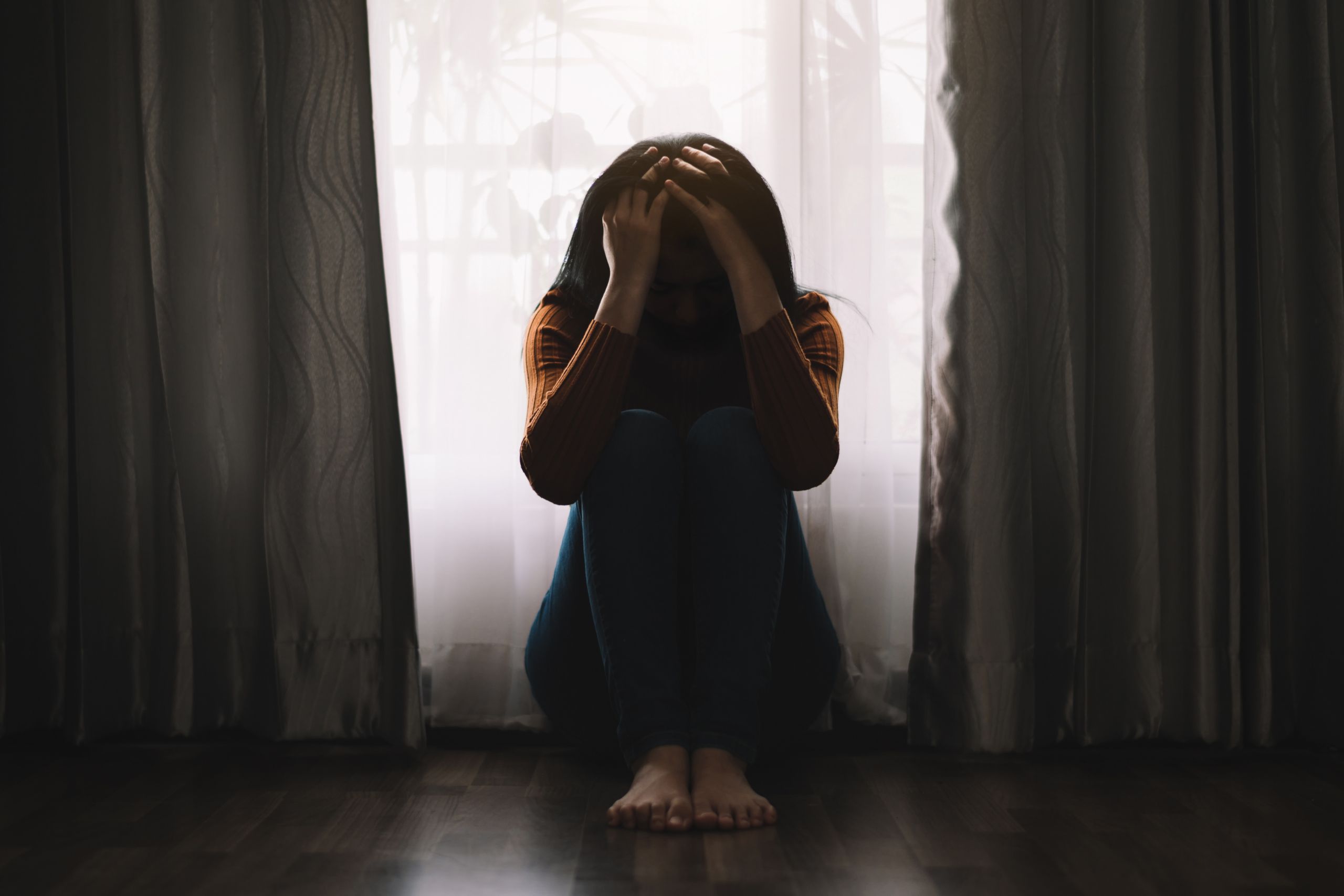 woman sitting on the floor holding her head struggling with different types of depression