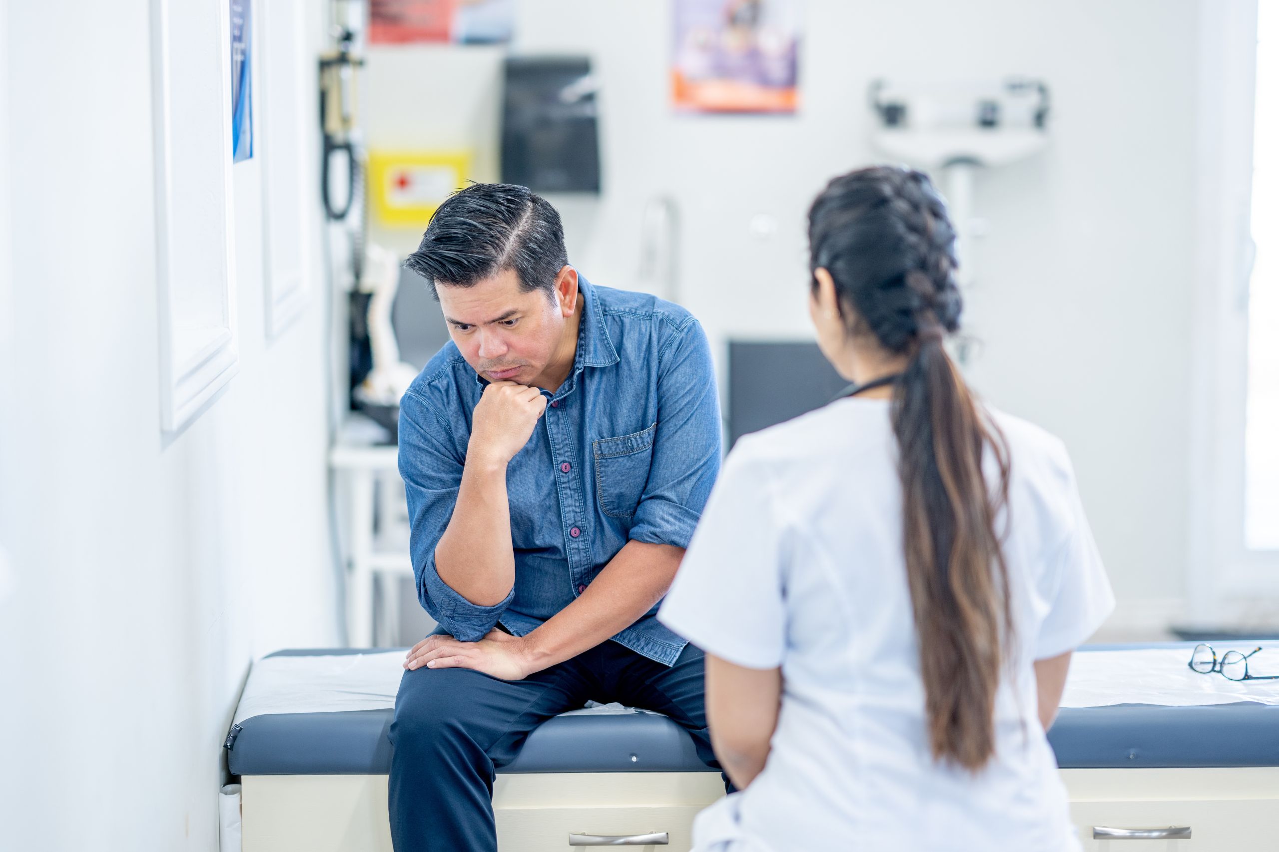 nurse speaking with male patient sitting on a hospital bed going over psych ward vs mental hospital