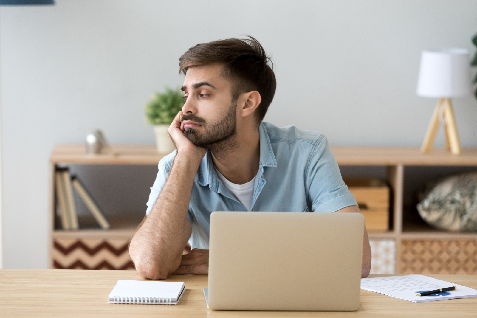 man sitting at his desk by a laptop getting distracted thinking about add vs adhd