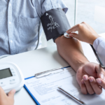 nurse taking a patients blood pressure while he is asking Can Anxiety Cause High Blood Pressure?